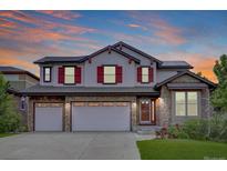 Charming two-story home featuring a stone facade, three-car garage, and striking red shutters at 24556 E Ottawa Ave, Aurora, CO 80016