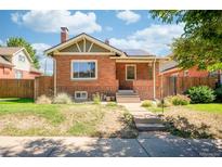 Charming red brick home featuring solar panels, a cozy front porch, and a well-manicured lawn at 4322 Decatur St, Denver, CO 80211