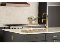 Modern kitchen featuring dark cabinetry, stainless steel appliances, marble countertops and gold fixtures at 4121 S Cherry St, Cherry Hills Village, CO 80113