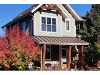 Charming two-story home with light green siding and a welcoming front porch, enhanced by vibrant red foliage at 9268 E 37Th Ave, Denver, CO 80238