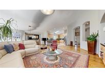 Spacious living room featuring hardwood floors, an area rug, and an open floor plan connecting to the kitchen at 9559 Brook Hill Ln, Lone Tree, CO 80124
