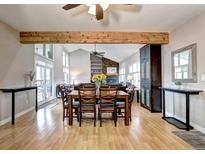 Open dining area with wood floors, large dining table, and seamless flow to a living room with fireplace at 7877 S University Way, Centennial, CO 80122