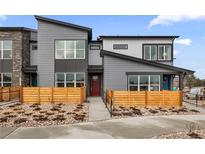 Contemporary townhouse featuring gray siding, a red front door, and stylish wood fencing and landscaping at 9445 W 58Th Cir # B, Arvada, CO 80002