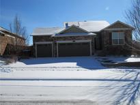 Charming, single-story home featuring a stone facade and a two-car garage in winter at 3212 S Kirk Way, Aurora, CO 80013
