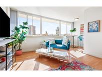 Bright living room featuring a comfortable blue sofa, large windows, and stylish decor at 1196 N Grant St # 405, Denver, CO 80203