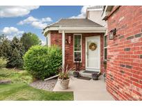 Charming brick home entrance with a white door, wreath, and beautiful landscaping at 9441 Southern Hills Cir, Lone Tree, CO 80124