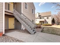 Charming condo with a yellow front door and grey wood siding at 3600 S Pierce St # 106, Lakewood, CO 80235