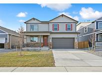 Charming two-story home featuring a covered porch, gray siding, red shutters, and a two-car garage at 27684 E Byers Ave, Aurora, CO 80018