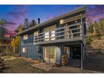 Charming home with a spacious deck and a cozy area to store wood, all surrounded by lush greenery at 779 Aspen Way, Evergreen, CO 80439