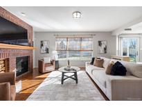 Bright living room featuring a brick fireplace, hardwood floors, and a large window at 1124 W 124Th Ct, Westminster, CO 80234