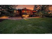Beautiful sunset view of a log cabin home with a large lawn and mature trees at 1353 S Elbert St, Elizabeth, CO 80107