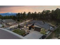Beautiful exterior view of home with lovely landscaping, mature trees and mountain views at sunset at 16244 Thunder Cat Way, Monument, CO 80132