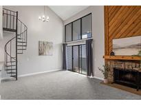 Inviting living room with a cozy fireplace, balcony, and modern spiral staircase at 14046 E Stanford Cir # I11, Aurora, CO 80015