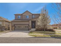 Two-story home with a two car garage, stone accents, tidy lawn, and blossoming tree at 1421 Rustic Dr, Longmont, CO 80504