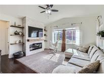 Bright living room featuring a fireplace, ceiling fan, and lots of natural light through the windows at 1421 Rustic Dr, Longmont, CO 80504