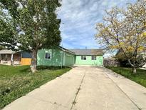 A charming single-story green home with a long driveway and front yard at 780 2Nd St, Bennett, CO 80102