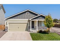 Charming home featuring a gray and light green exterior, two-car garage and a well-maintained lawn at 47341 Lily Ave, Bennett, CO 80102