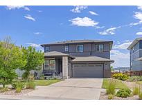 Two-story home with gray siding, attached two car garage, and a well manicured lawn and landscaping at 16486 W 94Th Dr, Arvada, CO 80007