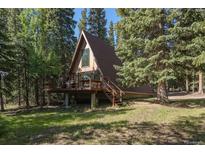 A-frame home with a brown exterior, surrounded by lush trees, featuring a wooden deck and staircase at 100 Aspen Ln, Evergreen, CO 80439