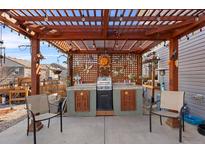 Outdoor patio with a wooden pergola, custom grill station, and cozy seating area at 2320 Morningview Ln, Castle Rock, CO 80109