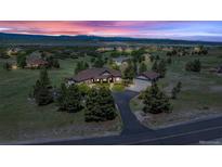Beautiful home with manicured lawn, mature trees and mountain views at sunset at 3535 Medallion Rd, Castle Rock, CO 80104