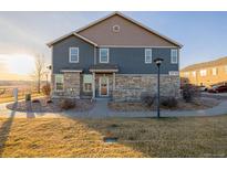 Two-story townhome with stone and siding exterior, landscaped yard, and attached garage at 12713 Leyden St # F, Thornton, CO 80602