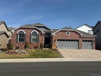 Charming brick home featuring a well-manicured front yard and an attached three-car garage at 20715 Bridlewood Ln, Parker, CO 80138