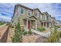 Attractive townhome with green siding, stone accents, colorful shutters, and a landscaped front yard at 16818 E 119Th Ave # A, Commerce City, CO 80022