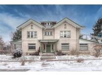 Charming brick home featuring a symmetrical design, covered entry and landscaped yard with winter snow at 1100 N Marion St # 4, Denver, CO 80218