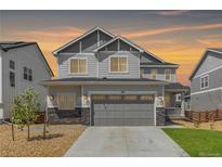 Inviting two-story home with a two car garage and stone accents against a sunset sky at 777 Gold Hill Dr, Erie, CO 80516