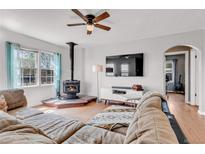Cozy living room featuring a wood-burning stove, ceiling fan, hardwood floors, and a comfortable sofa at 15205 W 43Rd Ave, Golden, CO 80403