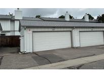 Attached one car garage with white door and adjacent parking in front of the home at 10320 E Jewell Ave # 63, Aurora, CO 80247