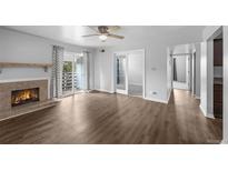 Spacious living room featuring a fireplace, ceiling fan, balcony, and hardwood floors at 7665 E Eastman Ave # 301A, Denver, CO 80231