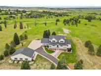 Stunning aerial view of the charming home with a separate garage surrounded by a vast green field at 3973 Palmer Ridge Dr, Parker, CO 80134