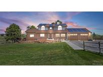 Charming brick two-story home featuring an attached garage, solar panels, and a beautifully manicured lawn at 9025 Rocky Mountain Ln, Parker, CO 80138