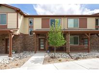 Attractive townhome featuring a stone facade, covered porch, and low maintenance landscaping with neutral color palettes at 11228 Bella Vita Dr, Broomfield, CO 80020
