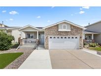 Charming home featuring a stone facade, well-manicured lawn, and a spacious two-car garage at 2034 Espana Way, Aurora, CO 80011