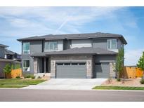 Beautiful two story home with gray siding, a stone facade, three car garage and modern architectural design at 14391 Shasta Daisy Pt, Parker, CO 80134