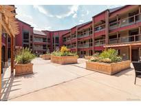 Beautiful condo courtyard featuring planter boxes with greenery, red exterior walls, and community space at 107 N Harris St # 306, Breckenridge, CO 80424
