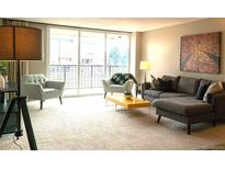 Bright living room featuring neutral carpet and contemporary furnishings, with a large sliding glass door at 2225 Buchtel Blvd # 202, Denver, CO 80210