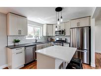 Modern kitchen featuring white cabinets, stainless steel appliances, and a stylish island with pendant lighting at 6220 W 11Th Pl, Lakewood, CO 80214