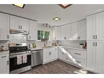 Bright kitchen features white cabinets, stainless steel appliances, tile backsplash, and wood-look flooring at 295 E Amherst Ave, Englewood, CO 80113