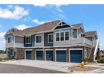 A modern townhome complex with a stone facade, multiple garage doors, and inviting curb appeal at 23743 E Ida Pl # E, Aurora, CO 80016