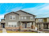Charming two-story home with gray siding, stone accents, and a welcoming front porch, perfect for suburban living at 765 Tarragon Rd, Brighton, CO 80640