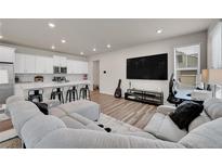 Open-concept living room showcases sleek floors and modern white kitchen at 765 Tarragon Rd, Brighton, CO 80640