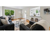 Inviting living room with hardwood floors, gray couches, white door, and a view to the kitchen at 3346 W 33Rd Ave, Denver, CO 80211