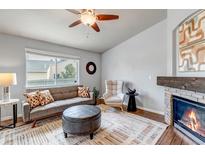 Cozy living room with decorative fireplace, gray sofa, and a ceiling fan at 2132 Boise Ct, Longmont, CO 80504