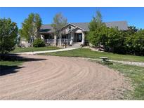 Charming home features a stone and siding exterior, covered porch, and beautifully landscaped front yard at 10515 Lucas Ave, Franktown, CO 80116
