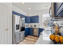 Well-lit kitchen featuring stainless steel appliances, navy blue cabinets, light countertops, and wood-look flooring at 13739 Legend Trl # 102, Broomfield, CO 80023