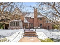 Beautiful brick home with manicured lawn and inviting entryway, framed by mature trees and winter's touch at 2020 E 4Th Ave, Denver, CO 80206